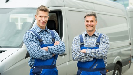 Versicherungen für Handwerksbetriebe: Zwei Handwerker vor ihrem Lieferwagen