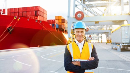 Gothaer Warentransportversicherung: Verantwortlicher Leiter vor Container-Schiff kümmert sich um den Transport.