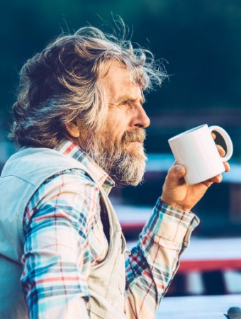 Pflegetagegeldversicherung: Ältere Herr trinkt eine Tasse Kaffee auf einer Terasse.