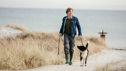Private Rente: Mann mit Hund in den Dünen - sorglos dank seiner privaten Rentenversicherung